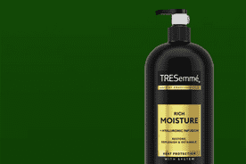 Image shows a black Tresemmé Rich Moisture moisturizing conditioner bottle with a pump on a dark green background.