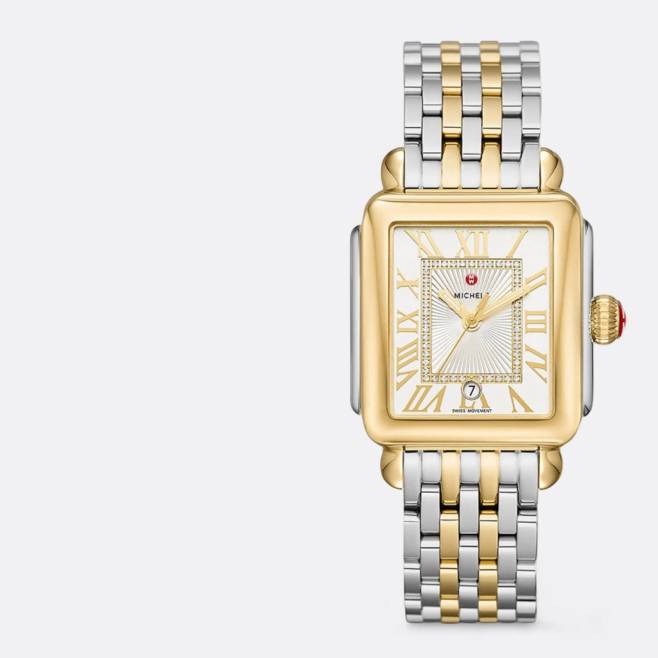 Silver and gold Michele watch is pictured on a light grey backdrop.
