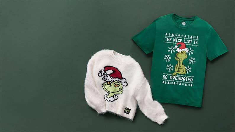 A Grinch sweater and a Grinch tee are pictured on a green backdrop.