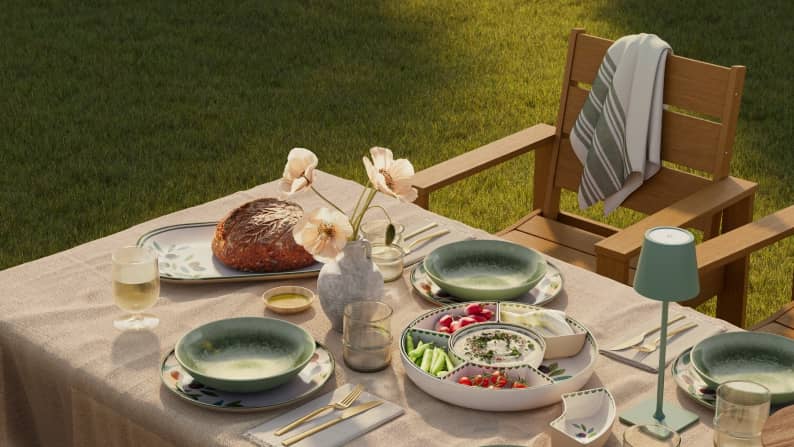 An outdoor table set with green bowls and a large divided serving tray filled with appetizers. Reads: Open-air hosting. From three twenty-eight.
