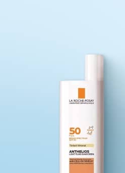 White sunscreen bottle with pump top displayed against a light blue background.