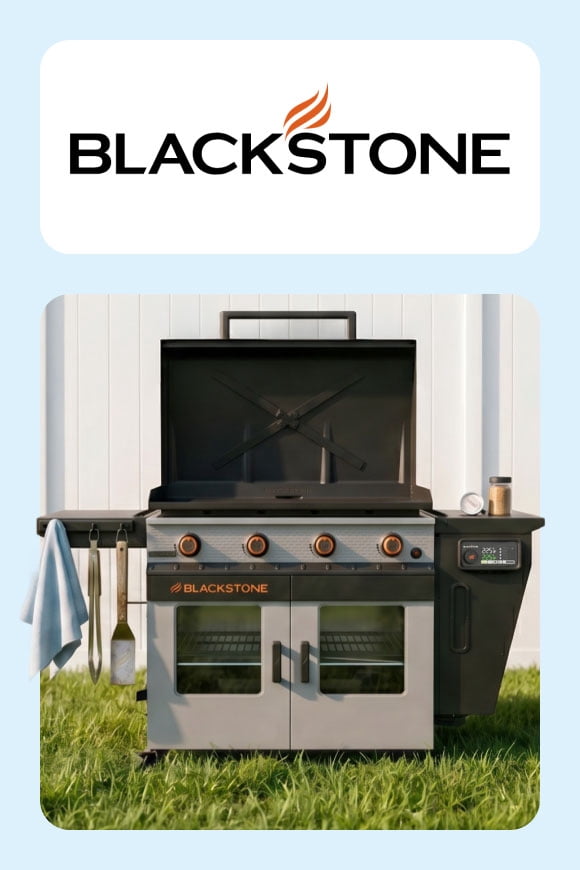 A grill on grass, in front of a white fence, across from the Blackstone logo.