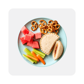 Plate with sandwich, pretzels, fruit and vegetables. 