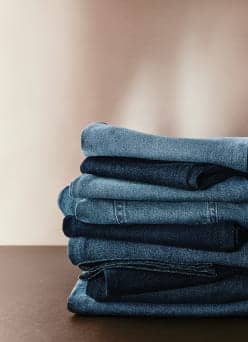 Stack of folded denim jeans in varying blue shades on a flat surface.