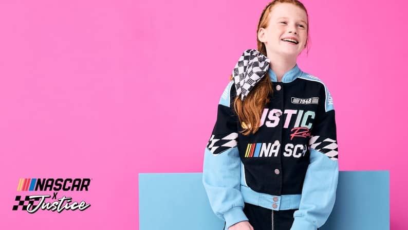 Nascar x Justice logo in the bottom left corner. A girl with a checkered bandana in her hair is wearing a color blocked jacket from the collection.