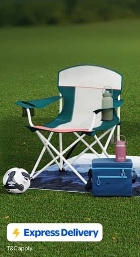 A blue and white camp chair, cooler, blanket, and soccer ball on a grassy field.