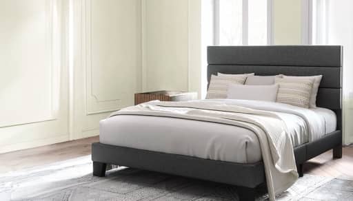 Bed made with bedding including sheets, bedspread, throw blanket, and pillows.