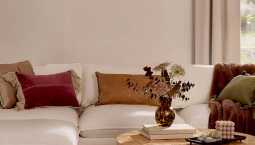 A mix of pillows in warm earthen colors and patterns is displayed on a jute rug.