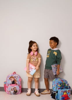 Two children wearing character-themed school outfits and headphones, with character-themed notebooks and backpacks.