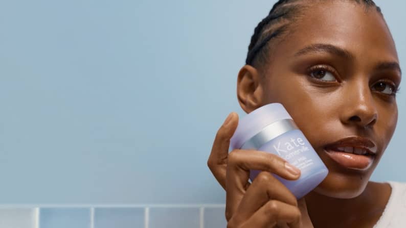 Image of a woman holding a skincare product near her face is shown.