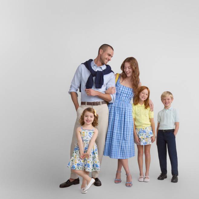 A family of five dressed in trendy Easter outfits is smiling together.