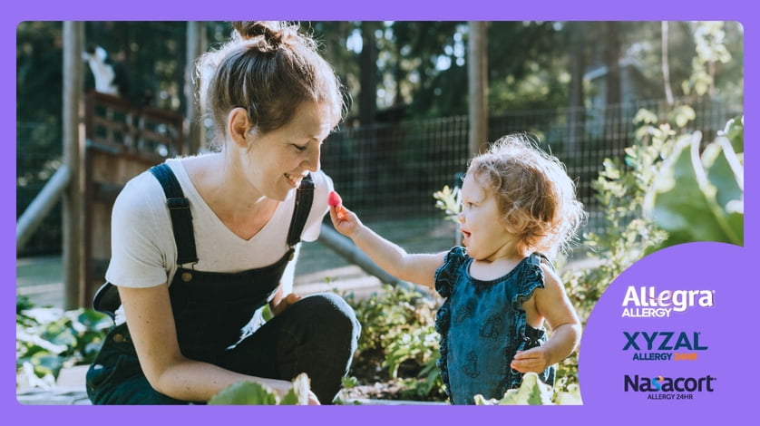 A daughter feeds her mother in a green garden.