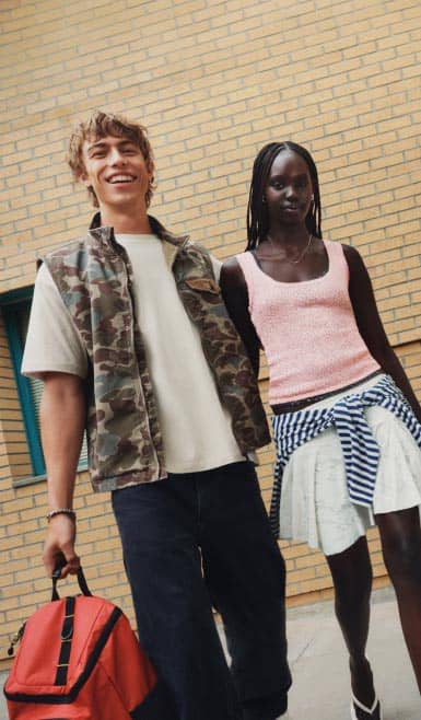 A young man carrying a backpack and a young woman wearing stylish clothes are walking together.