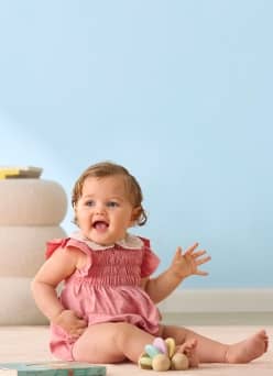 Baby girl with a plush toy and book on the floor.