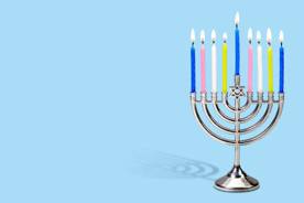 Image shows a lit menorah with colorful candles on a blue banner.