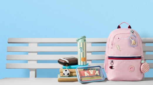 Patterned backpack on bench with water bottle, pencil cases, books and notebooks.