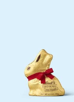 A Lindt gold milk chocolate bunny against a light blue background.