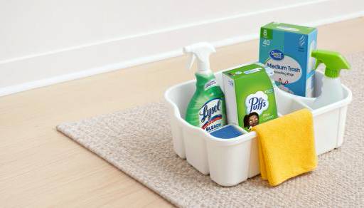 Lysol disinfecting spray, medium trash bags, puffs tissue paper, and a terry cloth towel in a cleaning caddy.
