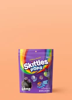 Skittles Popd chewy candy stand up pouch on a plain surface.