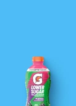 A bottle of rain berry Gatorade against a blue background.