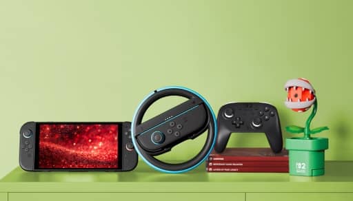 View a Nintendo Switch Two console and Piranha Plant Camera, a steering wheel with buttons at the center, video games and video game controller.