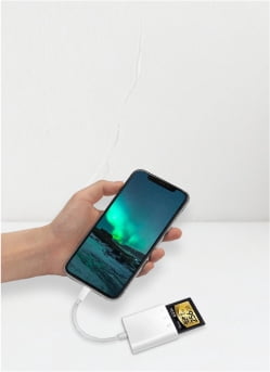Image of a black smartphone connected to a micro memory card adapter with a card in it.