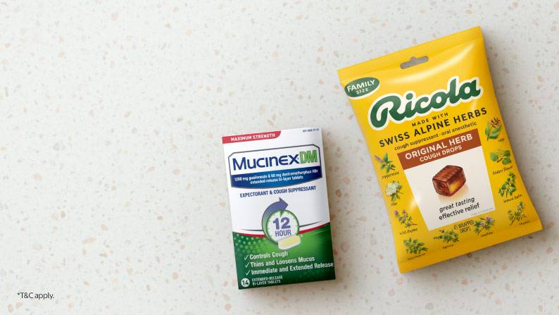 Image shows a box of Mucinex DM cough suppressant & a package of Ricola cough drops on a countertop.