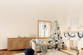 Image of a living room decorated with a flocked Christmas tree. The mantel and tree decor are all navy, light blue, and silver.