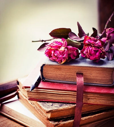 stack of old books with pink roses on top