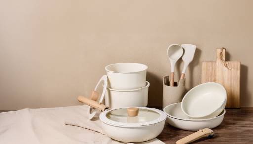 A stack of matching beige pots and dishes including a cutting board.