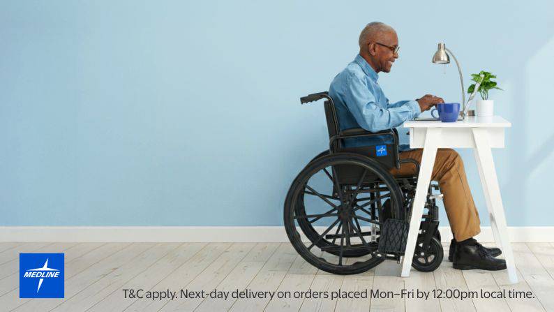 A man in a wheelchair sitting at a desk on a computer.