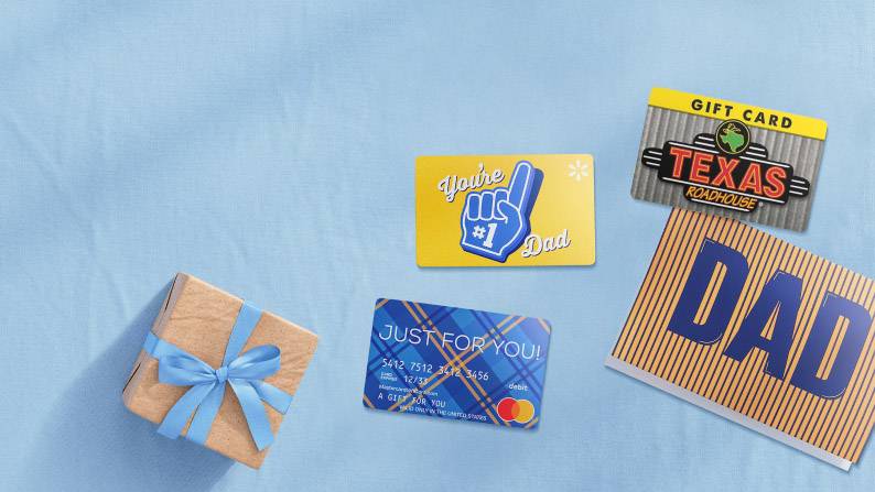 Yellow and blue gift cards on a blue background, next to a wrapped present and a card that says Dad.