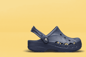 Image shows a navy blue Crocs Baya clog on a yellow background.