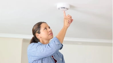 woman changing smoke detector