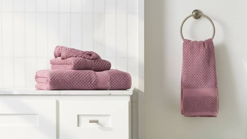 Mauve waffle-knit towel set on marble and white vanity.