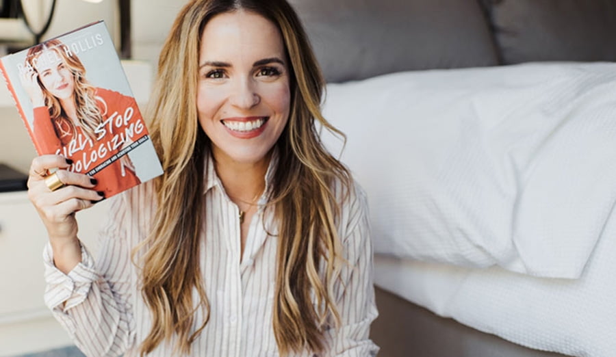 Rachel Hollis sitting and smiling. I guess she's by a bed.