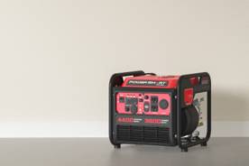 An image of a black and red generator on a grey floor against a beige wall.