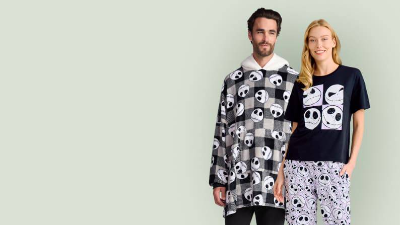 A man wearing a Jack Skellington hoodie and a woman wearing a Jack Skellington pajama set are pictured on a light green backdrop.