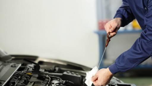 A hand working under the hood of a car.
