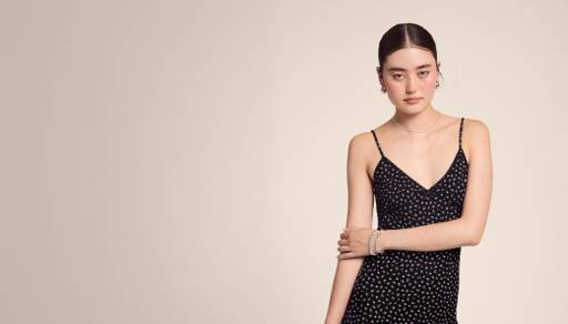 A young woman is shown wearing a black spaghetti strap mini dress.