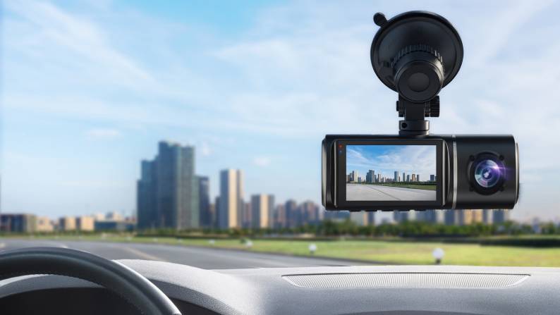 A dash cam in a front window, with a city skyline in the foreground.