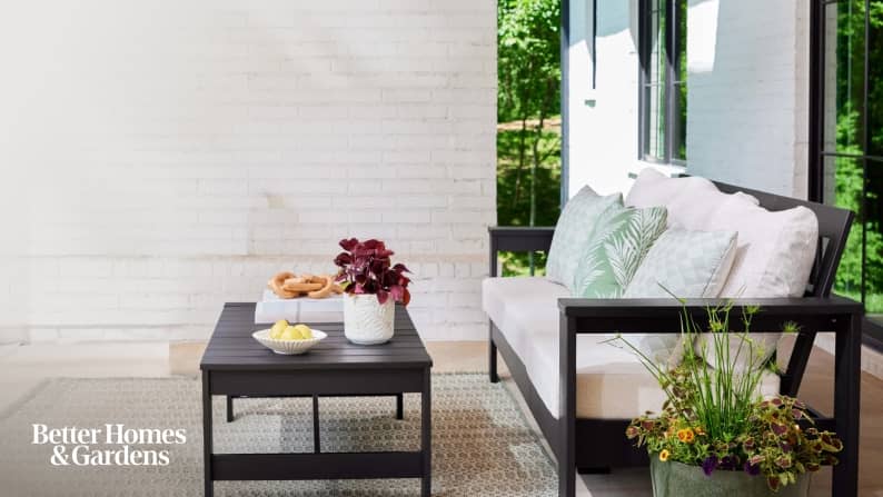 An assortment of patio furniture including tables, chairs, a rug and accessories arranged in a white and beige summer room.