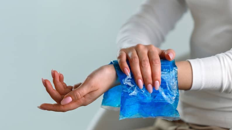 Hand reaching out with an icepack on wrist.