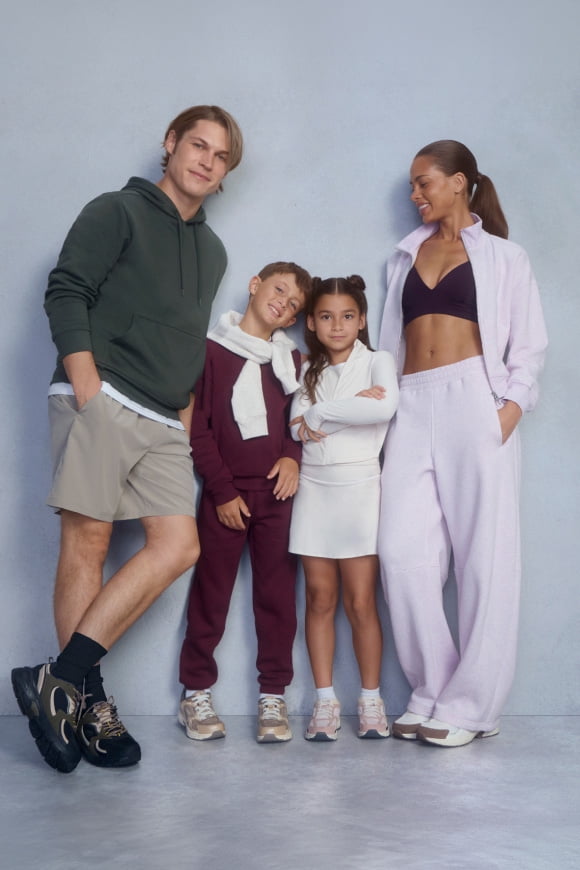 Family of four posing in white, beige, light purple and olive green activewear sets with sneakers.