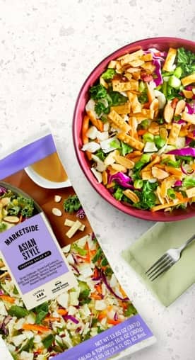 A bag of Marketside Asian style salad kit is shown, next to a bowl full of salad.