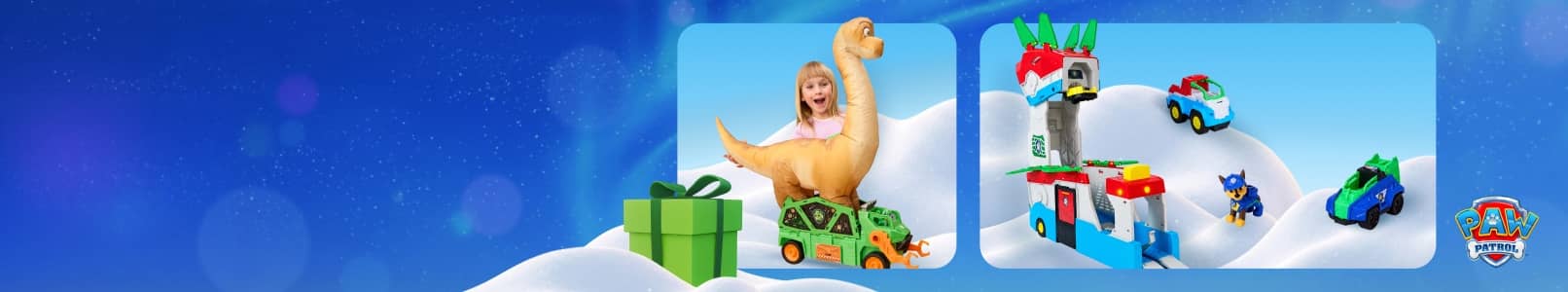 Child plays with large plush dinosaur and toy vehicles beside a green gift box and a snowy playset with small colorful cars.
