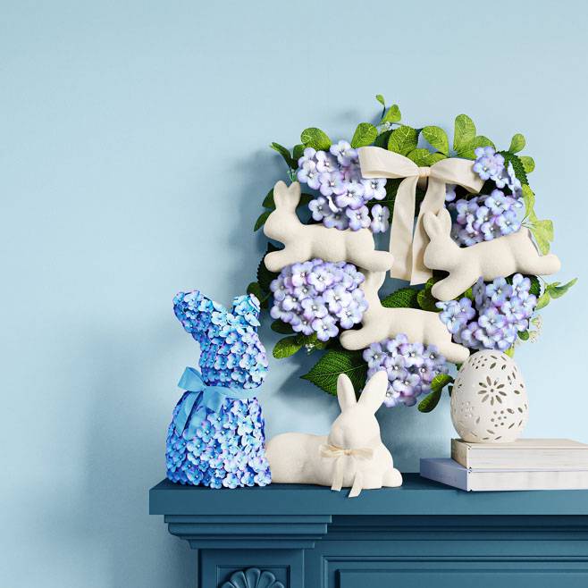 Bunny-shaped artificial flower arrangement, wreath with leaping bunnies as well as bunny and egg ornaments.