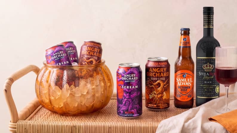 Angry Orchard hard cider cans and bottle, Samuel Adams Octoberfest beer and Stella Rosa wine on a woven tray with ice bucket and wine glass.