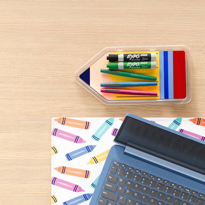 From $2.47. Markers, pens in a pencil-shaped holder, a laptop and a desk mat on a wood desk.