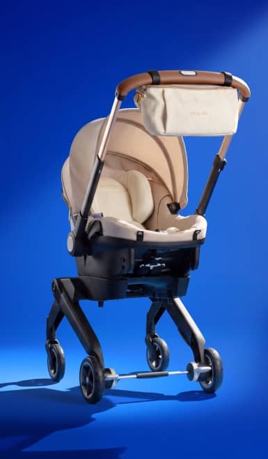Beige baby stroller with matching bag on handlebar.
